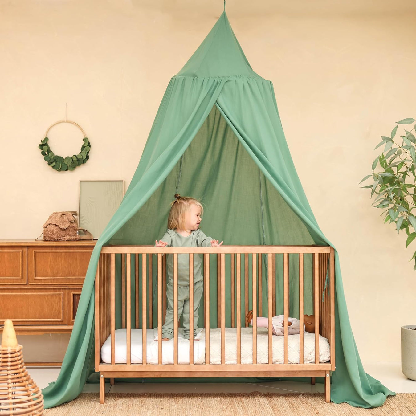 Green kids bed canopy hanging over crib in nursery room