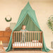 Green kids bed canopy hanging over crib in nursery room