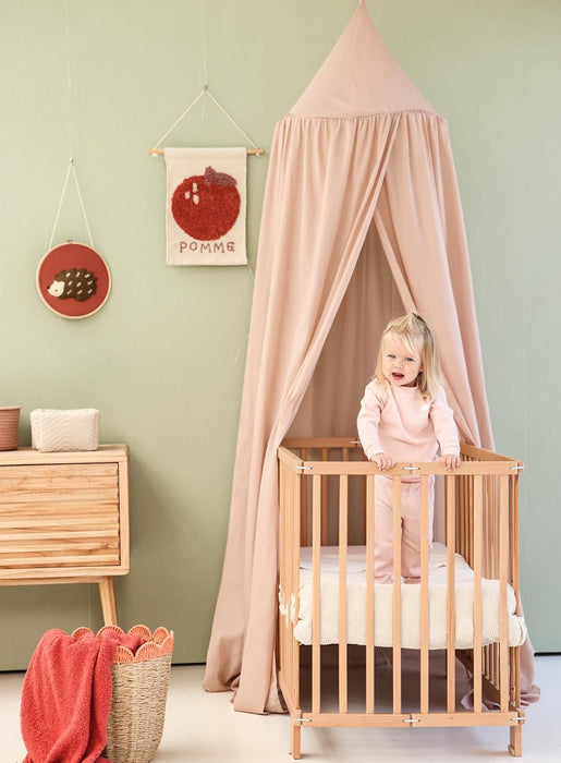 Nougat kids bed canopy hanging above crib in nursery room