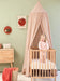 Nougat kids bed canopy hanging above crib in nursery room