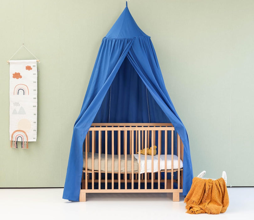 Green kids bed canopy hanging above crib in nursery room