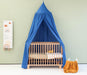 Green kids bed canopy hanging above crib in nursery room